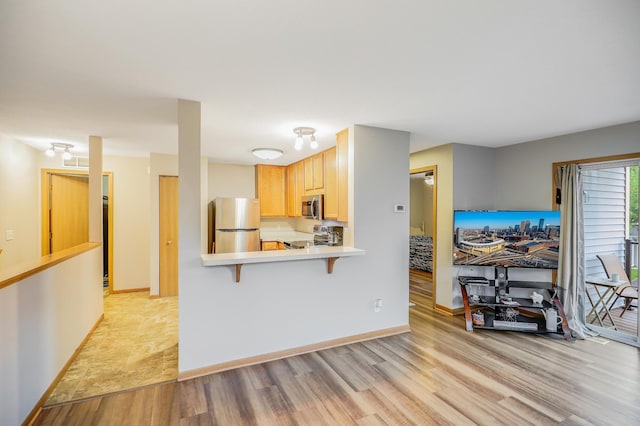 15521 Foghorn Ln, Apple Valley, MN 55124 - kitchen with stainless steel appliances, light wood-style flooring, light countertops, and a kitchen breakfast bar