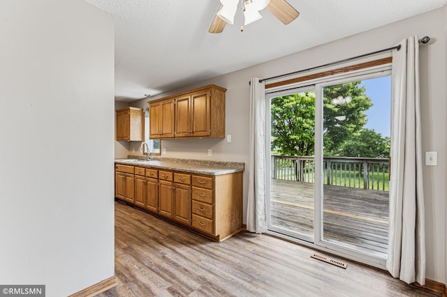 7216 Vinewood Ln N, Maple Grove, MN 55311 - kitchen featuring light wood-type flooring, a ceiling fan, light countertops, and brown cabinetry