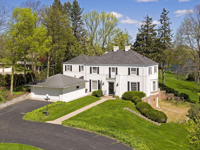 17950 Breezy Point Rd, Woodland, MN 55391 - colonial-style house with a chimney, stucco siding, a front yard, and a shingled roof