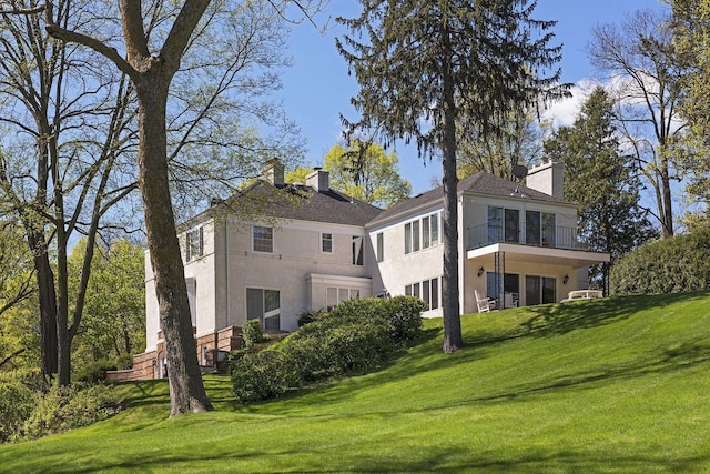 17950 Breezy Point Rd, Woodland, MN 55391 - back of property featuring stucco siding, a chimney, a lawn, and a balcony