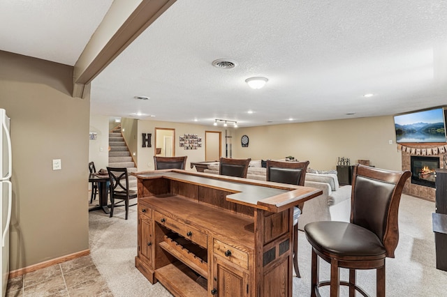 1364 Island View Dr, New Richmond, WI 54017 - bar with stairway, a glass covered fireplace, a textured ceiling, freestanding refrigerator, and light carpet