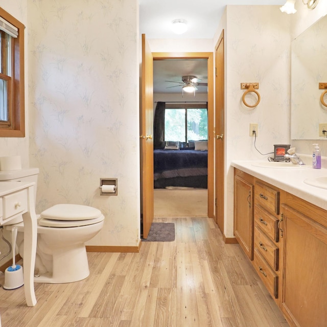 112 3rd St, Luck, WI 54853 - bathroom featuring wood finished floors, wallpapered walls, ensuite bath, double vanity, and ceiling fan
