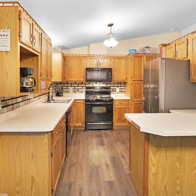 112 3rd St, Luck, WI 54853 - kitchen featuring black appliances, decorative backsplash, a peninsula, light wood-style floors, and light countertops