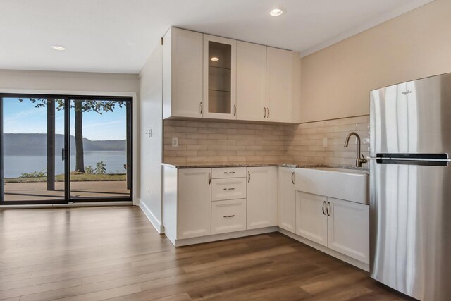 7 3rd St, Pepin, WI 54759 - kitchen with freestanding refrigerator, dark stone counters, backsplash, glass insert cabinets, and recessed lighting