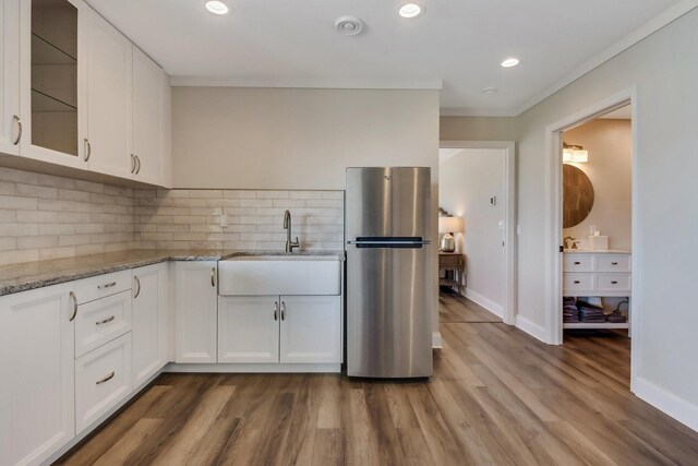 7 3rd St, Pepin, WI 54759 - kitchen featuring freestanding refrigerator, white cabinetry, tasteful backsplash, dark wood finished floors, and light stone counters