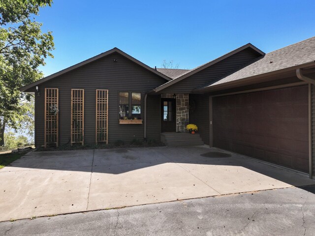 7 3rd St, Pepin, WI 54759 - view of front of property with driveway, an attached garage, roof with shingles, and stone siding