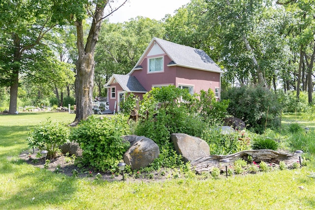 37245 US Highway 59 SE, Knute Twp, MN 56556 - view of side of property featuring a yard, stucco siding, a shingled roof, and view of wooded area