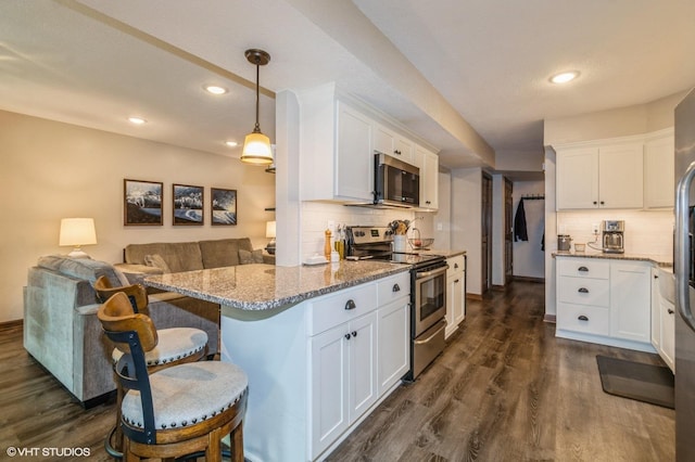 1007 124th Cir NW, Coon Rapids, MN 55448 - kitchen with appliances with stainless steel finishes, backsplash, white cabinetry, light stone counters, and a kitchen breakfast bar