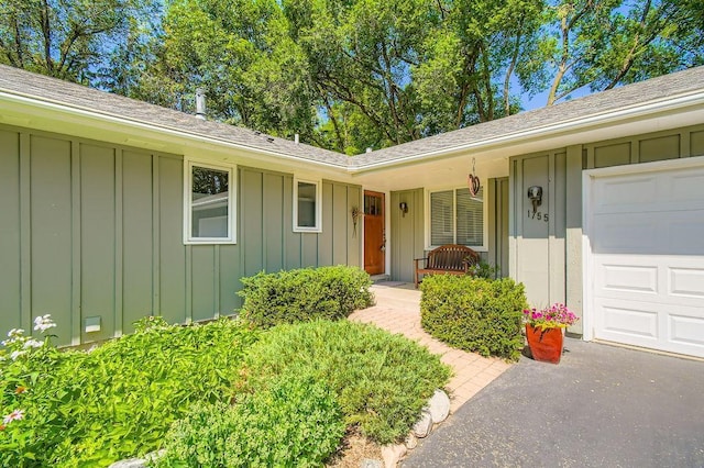1755 Ranier Ln N, Plymouth, MN 55447 - property entrance featuring board and batten siding, roof with shingles, a porch, and an attached garage