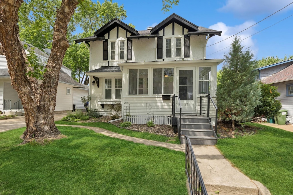 117 9th Ave NW, Rochester, MN 55901 - english style home with a front yard, stucco siding, and a sunroom