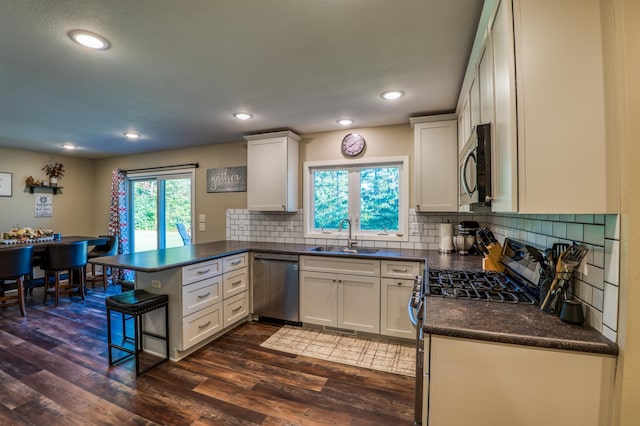 329 Kelliher Rd SW, Kelliher, MN 56650 - kitchen featuring appliances with stainless steel finishes, a peninsula, dark countertops, tasteful backsplash, and dark wood-type flooring
