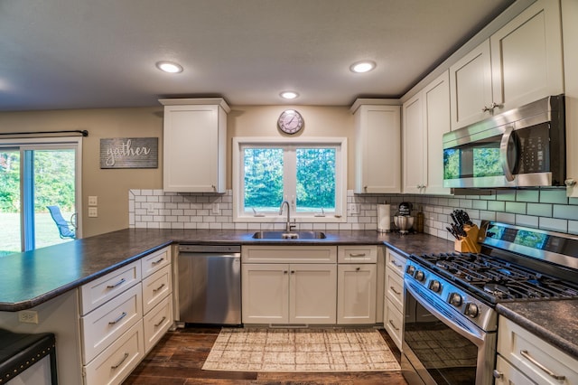 329 Kelliher Rd SW, Kelliher, MN 56650 - kitchen with appliances with stainless steel finishes, a peninsula, dark countertops, dark wood finished floors, and tasteful backsplash