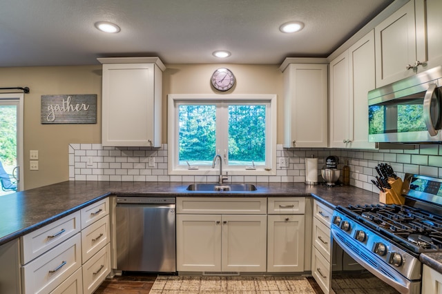 329 Kelliher Rd SW, Kelliher, MN 56650 - kitchen featuring stainless steel appliances, dark countertops, tasteful backsplash, white cabinets, and recessed lighting