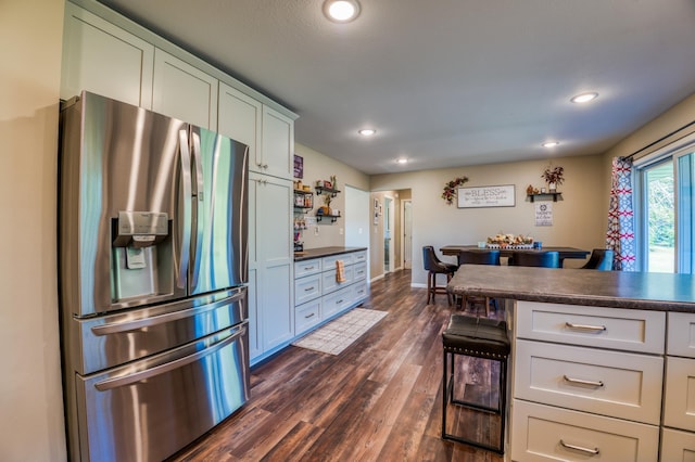 329 Kelliher Rd SW, Kelliher, MN 56650 - kitchen with stainless steel fridge with ice dispenser, dark countertops, dark wood-type flooring, recessed lighting, and a breakfast bar area