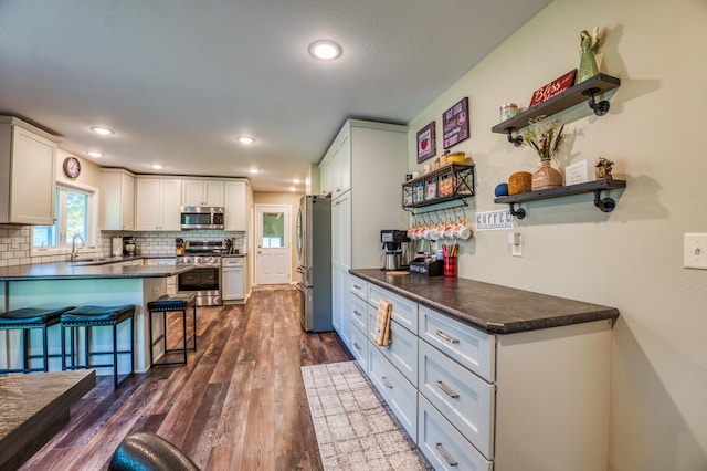 329 Kelliher Rd SW, Kelliher, MN 56650 - kitchen with appliances with stainless steel finishes, a breakfast bar, backsplash, dark countertops, and dark wood-style floors