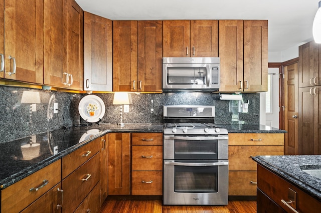8544 Demontreville Trl N, Lake Elmo, MN 55042 - kitchen with appliances with stainless steel finishes, dark wood finished floors, dark stone counters, and decorative backsplash