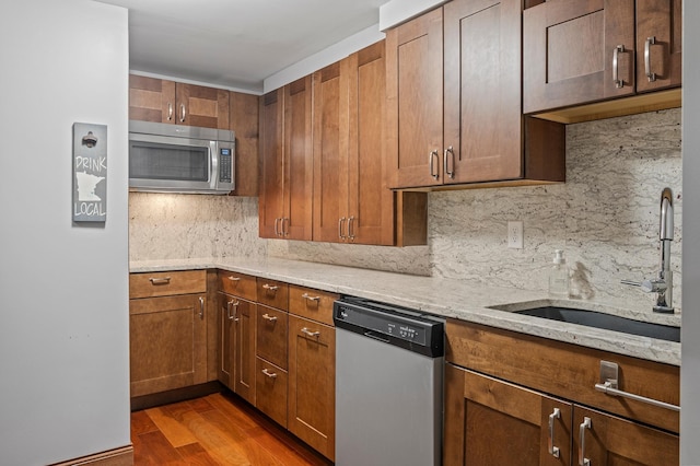 8544 Demontreville Trl N, Lake Elmo, MN 55042 - kitchen featuring appliances with stainless steel finishes, backsplash, light stone counters, dark wood finished floors, and brown cabinetry