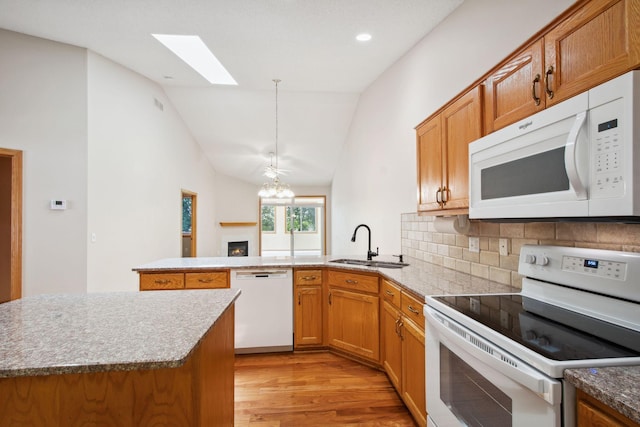14208 Heritage Ln, Apple Valley, MN 55124 - kitchen with white appliances, light wood-style flooring, a peninsula, brown cabinetry, and vaulted ceiling