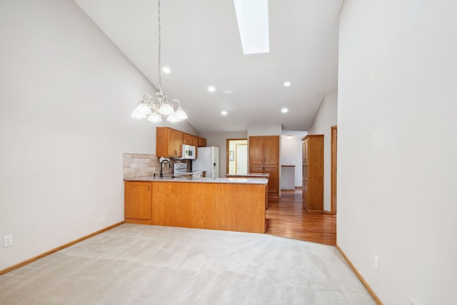 14208 Heritage Ln, Apple Valley, MN 55124 - kitchen with white appliances, a peninsula, light countertops, a chandelier, and a skylight