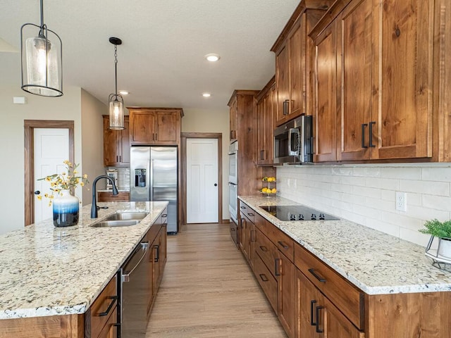 1136 168th Ln NW, Andover, MN 55304 - kitchen with appliances with stainless steel finishes, brown cabinetry, light wood-type flooring, light stone counters, and a kitchen island with sink