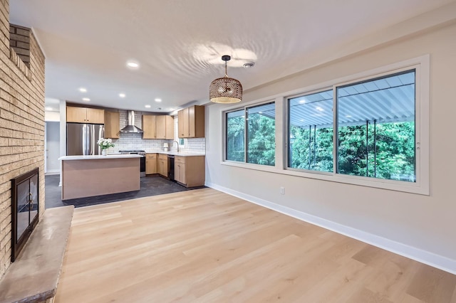12258 Crooked Lake Blvd NW, Coon Rapids, MN 55433 - kitchen featuring stainless steel appliances, wall chimney exhaust hood, light countertops, backsplash, and light wood-type flooring