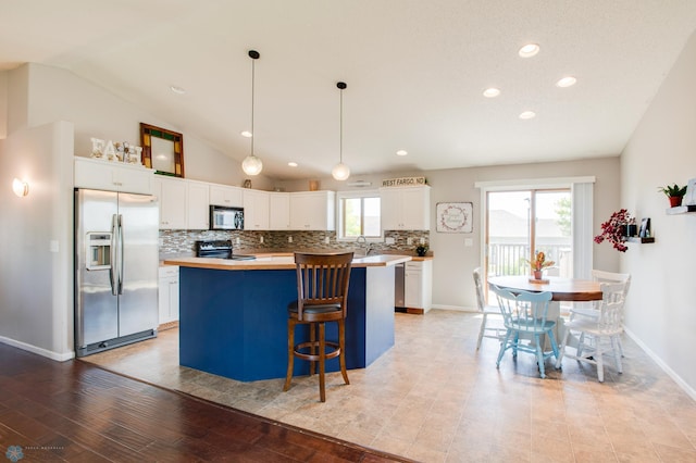 1083 Parkway Ln, West Fargo, ND 58078 - kitchen featuring appliances with stainless steel finishes, tasteful backsplash, a kitchen island, white cabinets, and butcher block counters