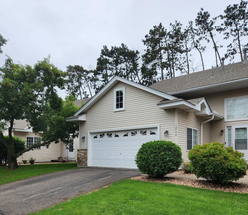 12748 Ulysses Cir NE, Blaine, MN 55434 - view of front facade featuring driveway, a garage, a front lawn, and roof with shingles