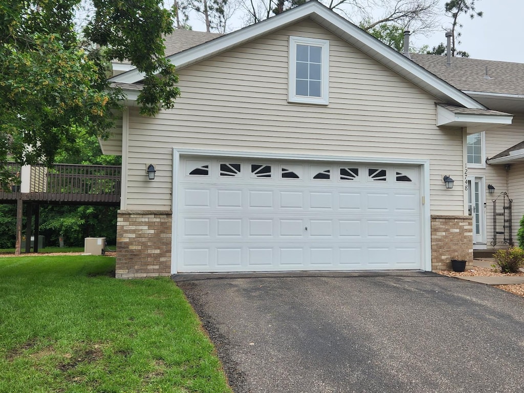 12748 Ulysses Cir NE, Blaine, MN 55434 - view of front of house featuring brick siding, asphalt driveway, roof with shingles, and a front lawn