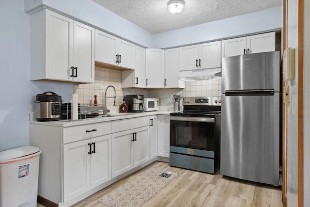4421 Cinnamon Ridge Cir, Eagan, MN 55122 - kitchen with stainless steel appliances, under cabinet range hood, a textured ceiling, white cabinetry, and light wood finished floors