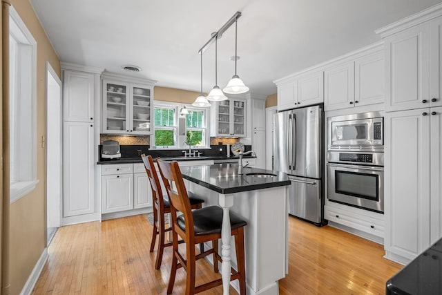 123 Franklin Ave, Owatonna, MN 55060 - kitchen featuring appliances with stainless steel finishes, dark countertops, decorative backsplash, and light wood-style floors