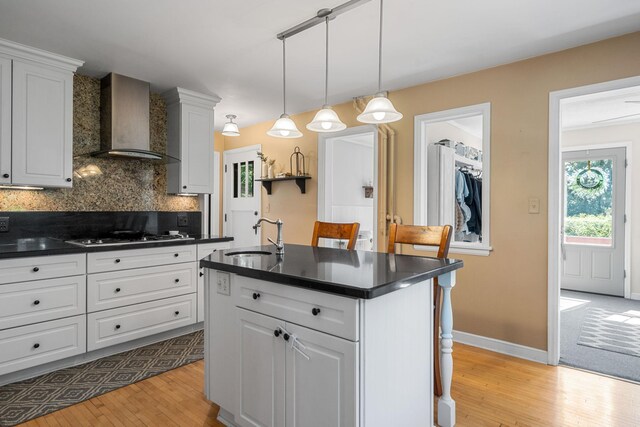 123 Franklin Ave, Owatonna, MN 55060 - kitchen featuring wall chimney range hood, gas stovetop, dark countertops, light wood-style floors, and backsplash
