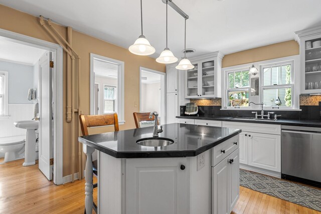 123 Franklin Ave, Owatonna, MN 55060 - kitchen with dishwasher, dark countertops, light wood-style flooring, a center island with sink, and decorative backsplash