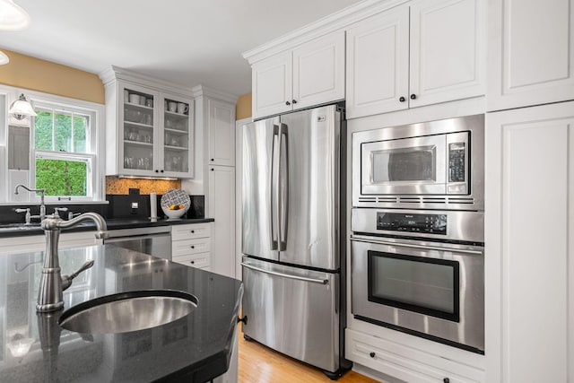 123 Franklin Ave, Owatonna, MN 55060 - kitchen featuring appliances with stainless steel finishes, glass insert cabinets, white cabinetry, backsplash, and light wood-style floors