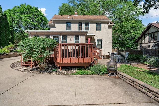123 Franklin Ave, Owatonna, MN 55060 - rear view of house with stucco siding, a patio, a wooden deck, and a chimney