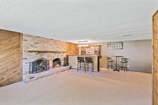 4982 148th Path W, Apple Valley, MN 55124 - carpeted living room featuring a fireplace, wood walls, bar, and a textured ceiling