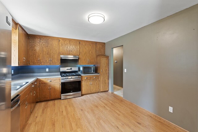 4982 148th Path W, Apple Valley, MN 55124 - kitchen with stainless steel appliances, under cabinet range hood, light wood-style floors, brown cabinetry, and light countertops