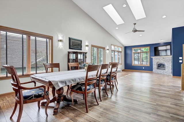 308 Iowa St, Lake City, MN 55041 - dining room featuring high vaulted ceiling, a skylight, light wood-type flooring, a stone fireplace, and ceiling fan