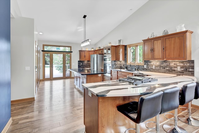 308 Iowa St, Lake City, MN 55041 - kitchen with stainless steel double oven, brown cabinets, a kitchen island, tasteful backsplash, and vaulted ceiling