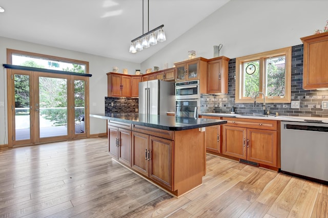 308 Iowa St, Lake City, MN 55041 - kitchen featuring appliances with stainless steel finishes, brown cabinets, light wood finished floors, backsplash, and vaulted ceiling