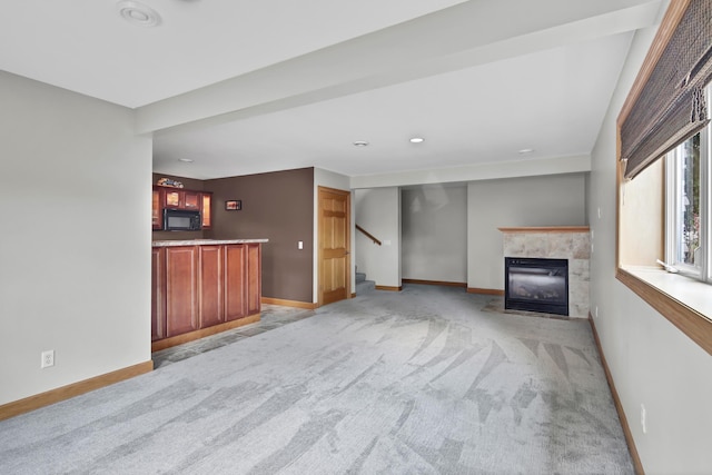 308 Iowa St, Lake City, MN 55041 - unfurnished living room with a tile fireplace, light colored carpet, and stairs