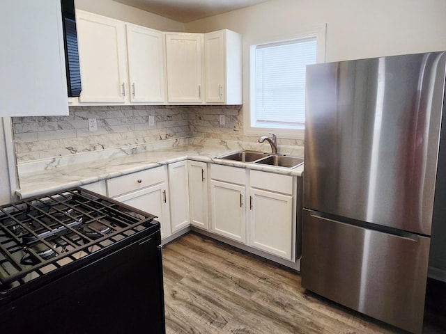 1222 8th Ave SE, Rochester, MN 55904 - kitchen featuring freestanding refrigerator, black gas range, white cabinetry, light wood-type flooring, and decorative backsplash