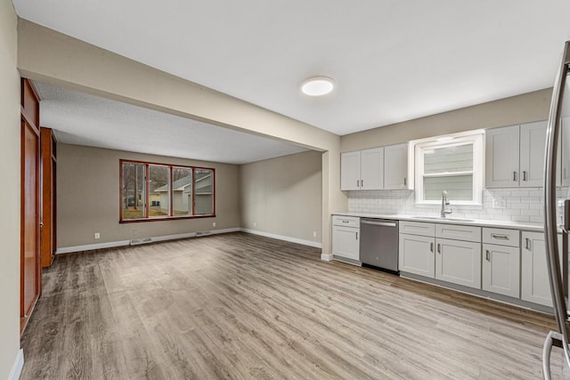710 Jefferson St, New Ulm, MN 56073 - kitchen featuring stainless steel dishwasher, decorative backsplash, light wood-type flooring, light countertops, and open floor plan