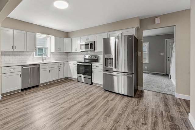 710 Jefferson St, New Ulm, MN 56073 - kitchen with stainless steel appliances, light countertops, decorative backsplash, light wood-style floors, and white cabinetry