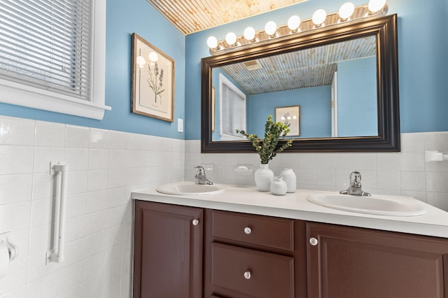 12329 Timber Ln, Maple Grove, MN 55369 - bathroom featuring tile walls, double vanity, and a wainscoted wall