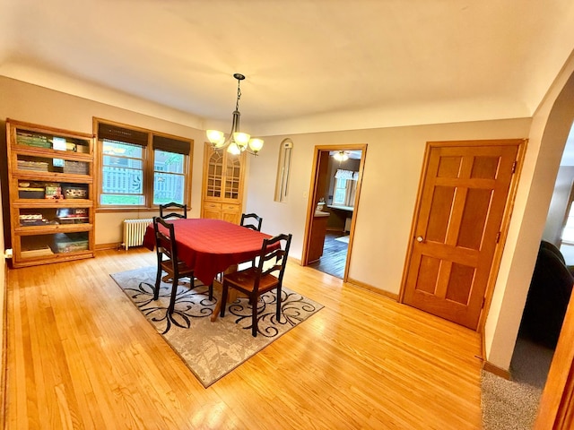 215 1st St N, Cannon Falls, MN 55009 - dining room with radiator, light wood-style flooring, a chandelier, and arched walkways