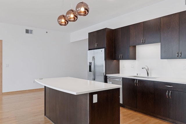 1240 2nd St Unit 1024, Minneapolis, MN 55415 - kitchen featuring appliances with stainless steel finishes, light countertops, light wood-style floors, a center island, and dark brown cabinetry
