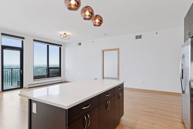 1240 2nd St Unit 1024, Minneapolis, MN 55415 - kitchen featuring a baseboard radiator, freestanding refrigerator, light wood-style floors, light countertops, and a kitchen island