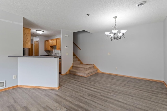 10787 Unity Ln N, Brooklyn Park, MN 55443 - kitchen with dark countertops, wood finished floors, a textured ceiling, a chandelier, and decorative light fixtures