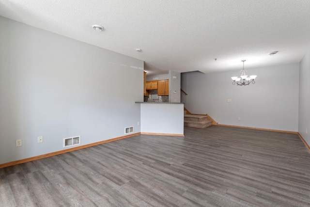 10787 Unity Ln N, Brooklyn Park, MN 55443 - unfurnished living room with wood finished floors, a chandelier, stairs, and a textured ceiling