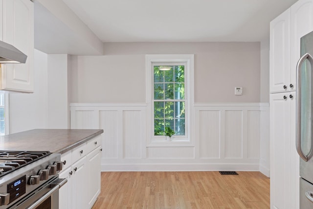 721 Smith Ave S, Saint Paul, MN 55107 - kitchen with a wainscoted wall, light wood-style floors, white cabinets, and a decorative wall